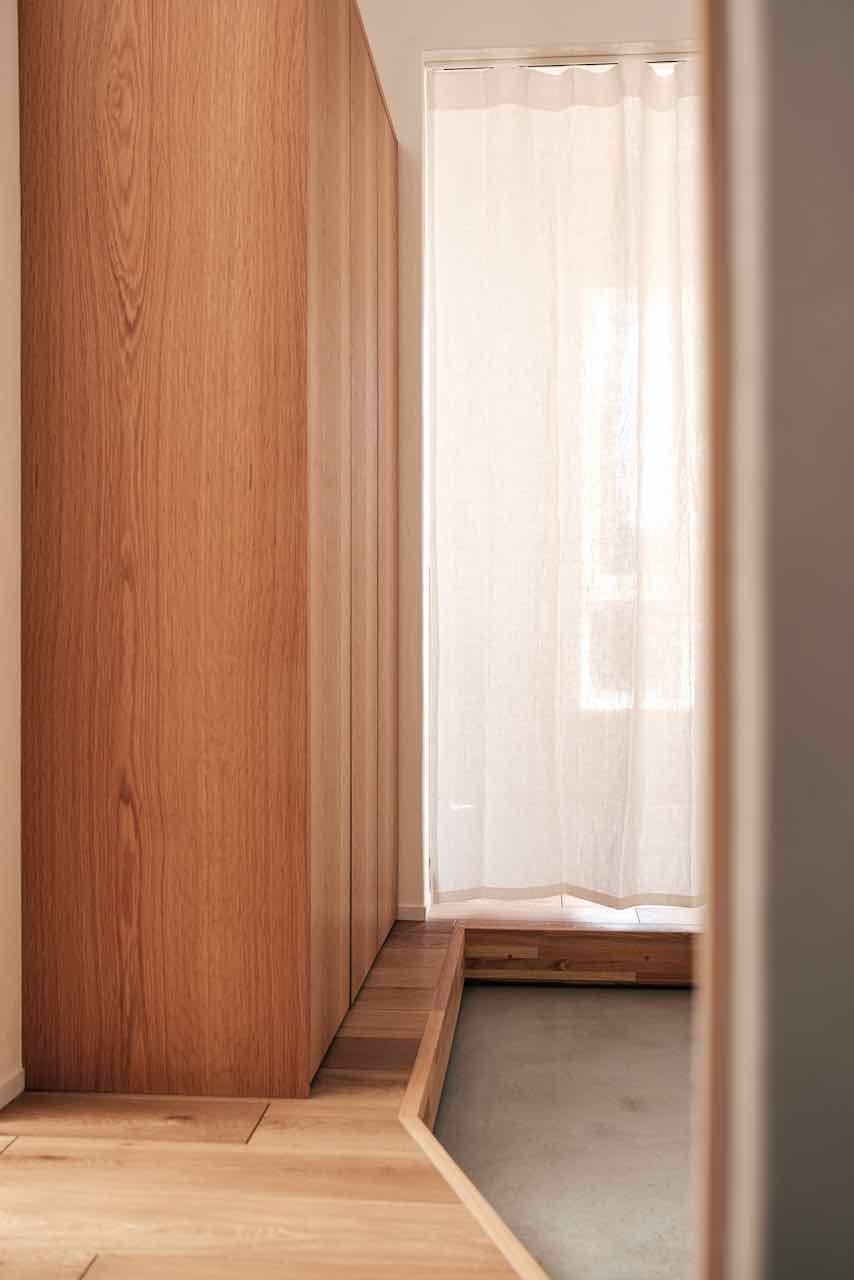 ナラ材の玄関収納とリネンカーテンのゆらぎ。